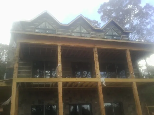 Dormers and porch framing on a large log home under construction — Roof Coating work by our crew in Sorrento