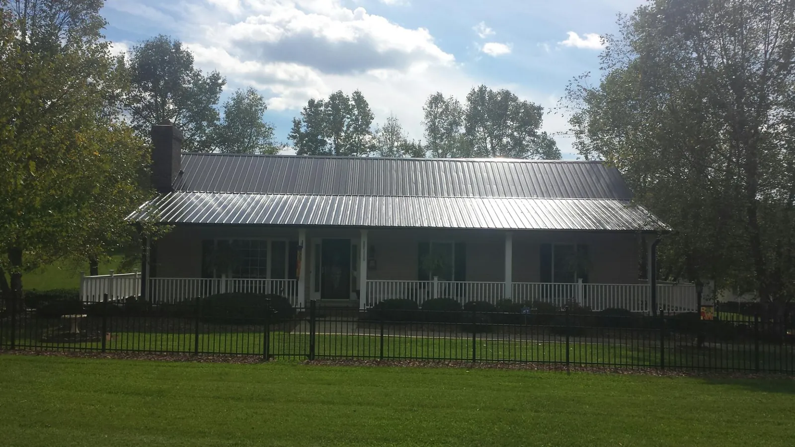 Gray metal roof on a brick ranch with a full width front porch — Gutter Guard Installation work by our crew in Sorrento