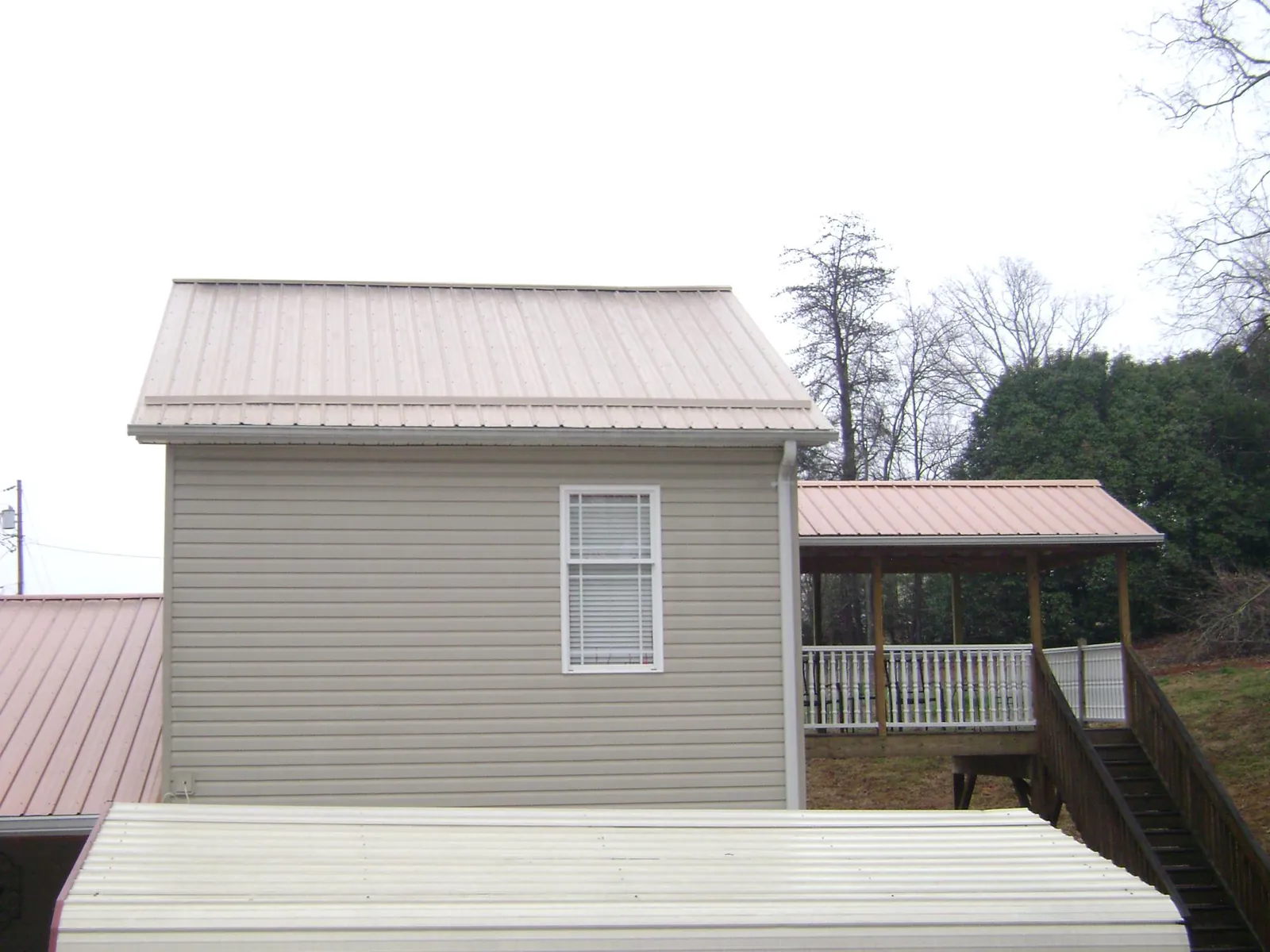Tan metal roofs on a two story addition and attached porch, from a Roof Replacement job in Sorrento