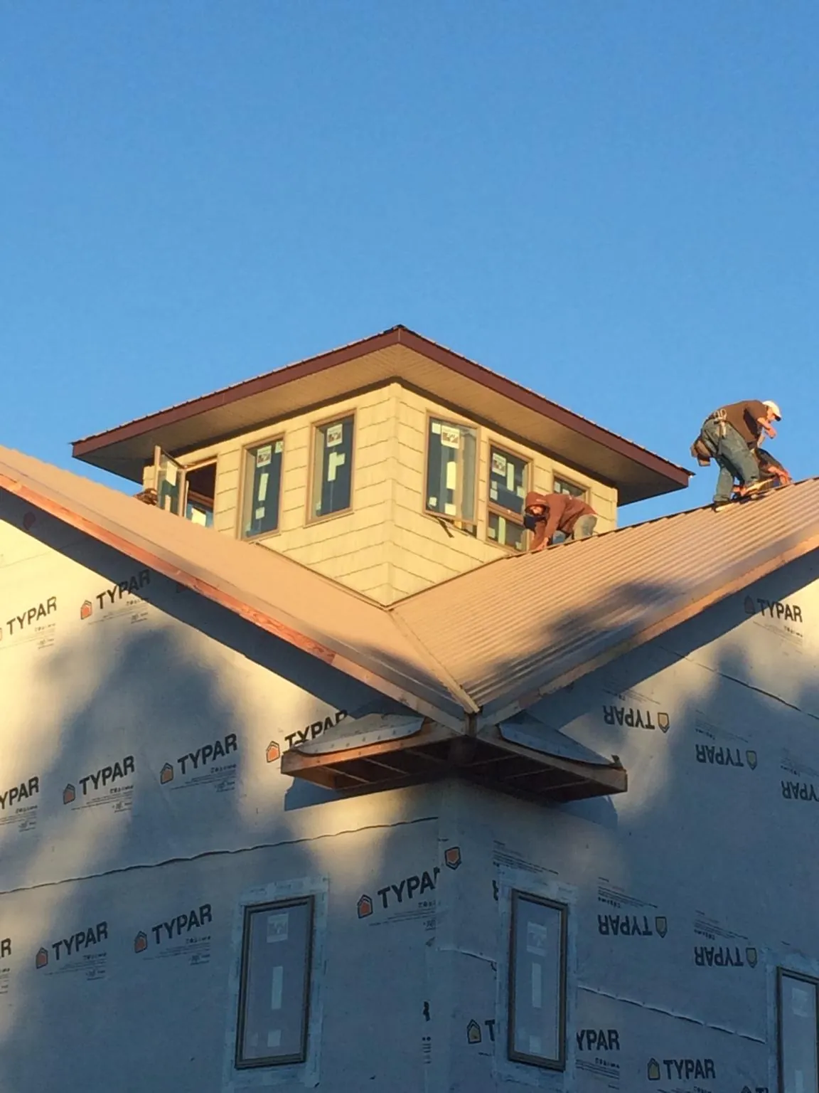 Roofers working around a rooftop cupola on a new metal roof at sunset — Roof Waterproofing in Sorrento by Roofing Brothers